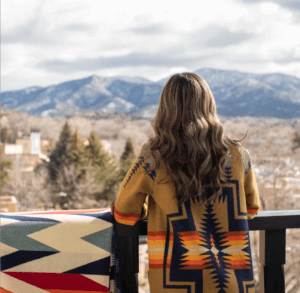 Woman standing on the balcony of La Fonda looking toward the mountains.
